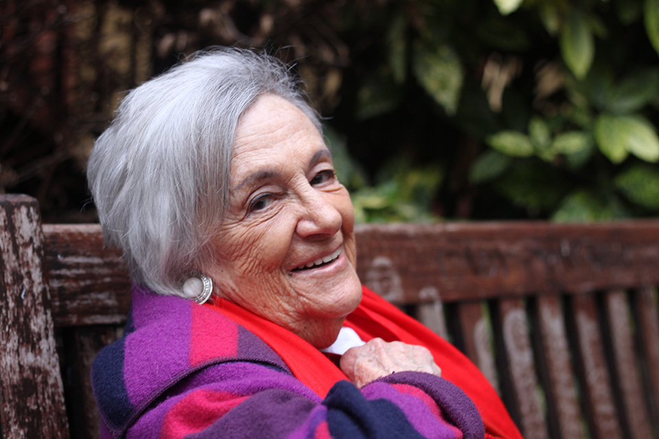 Geraldine Frank sat against a bench and smiling at the camera